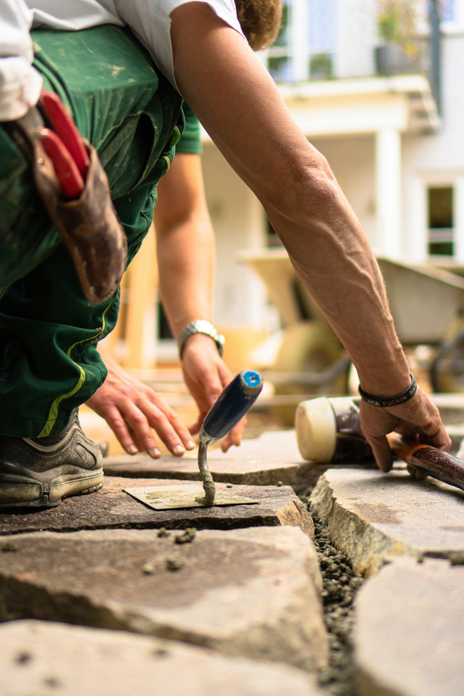 A tradesman's hands setting stone with a trowel
